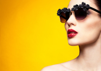 Fashion portrait woman in glasses over yellow background 