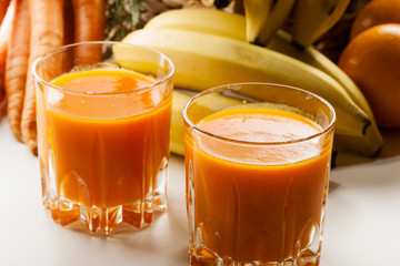 Glass of fruit juice with orange, carrots and banana