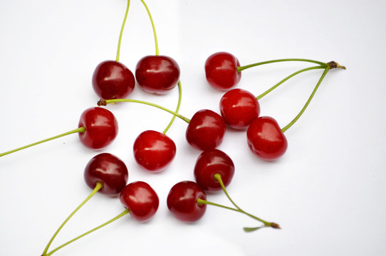 Ripe red fruit cherries with stalks on a white background