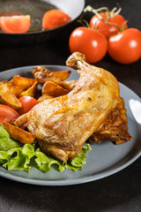 Roasted chicken legs with potato wedges and tomatoes