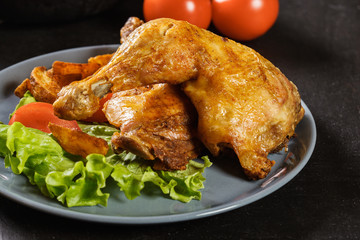 Roasted chicken legs with potato wedges and tomatoes