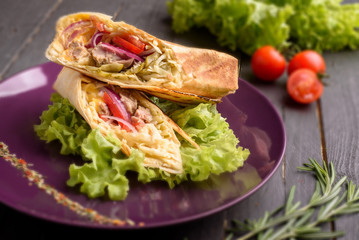 Fast food shawarma pita dish on a purple plate with cherry tomato