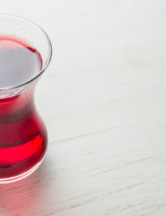 Hibiscus tea in a glass mug on a wooden table among rose petals and dry tea custard