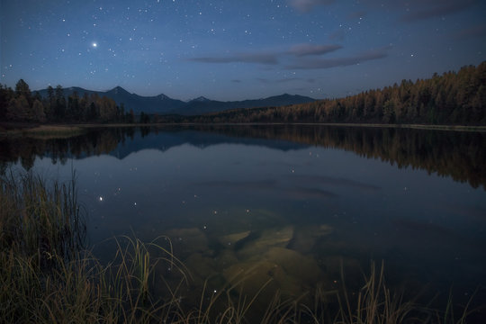 Mirror Surface Lake Autumn Landscape With Mountain Range In Early Eveing With Stars On The Sky