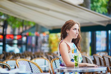 Woman in Parisian cafe with cocktail on a summer day