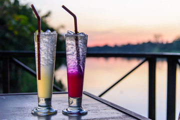 cocktail in the glass with sunset view / beverage with sunset at the lake view