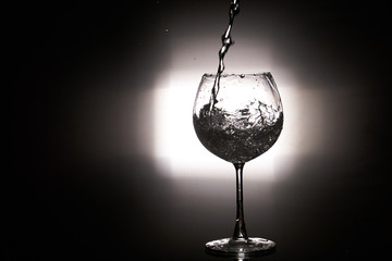 Water splashing wine glass black background with light