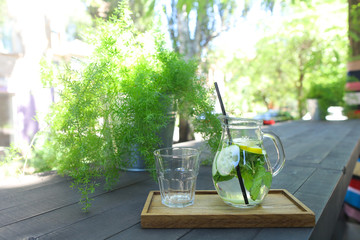 Glass decanter and glass faceted cup stands on plank on table in