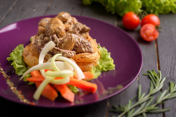 Hot tasty meat dish on purple plate with cherry tomato