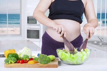 Expectant mother makes salad with a bowl