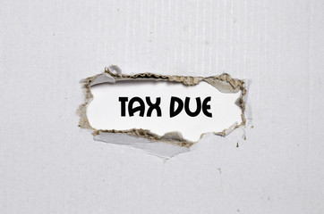 The word tax due appearing behind torn paper