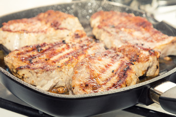 Fresh pork steak with spices cooking on teflon pan grill. Shallow depth of field.