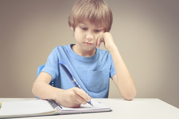 Naklejka na ściany i meble Boy writing on paper notebook. Boy doing his homework exercises