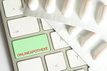 Tabletten und ein Computer mit der Taste für Online Apotheke