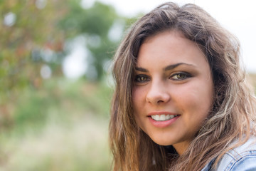 Fototapeta premium Portrait of smiling long hair brunette teenage girl outdoors closeup.
