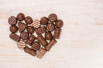 Heart made from chocolate truffles on wooden background.