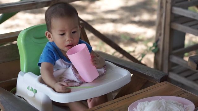 10 months Asian baby drinks water by himself
