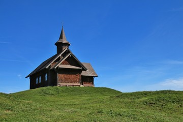 Fototapeta na wymiar Timber chapel on a green hill in Stoos, Switzerland.