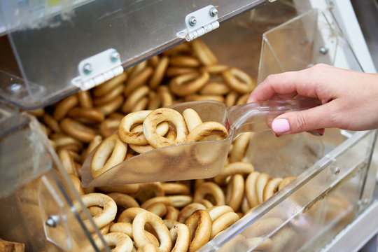 Woman buyer in shop buys bagels using scoop for products