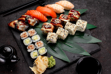 Japanese cuisine. Sushi set on a stone plate and dark concrete background