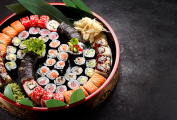 Obraz na płótnie Canvas Japanese cuisine. Sushi set on a round wooden plate and dark concrete background.