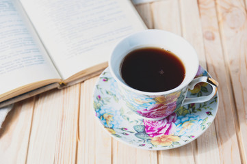 Cozy home still life: cup of hot coffee or tea and opened book