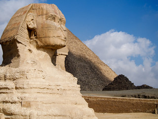 Ancient sphinx statue in front of the Great Pyramids of Giza in the desert near Cairo Egypt.