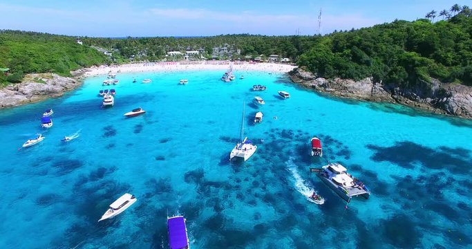 Racha Island Beach. Thailand, Phuket. Yachts , Catamarans and Boats sailing in crrystal clear blue water of ocean. Flying from ocean to sandy beach. Aerial view. 4K.