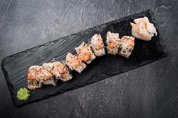 Tasty and delicious traditional japanese sushi roll with seafood and fish on black wooden background