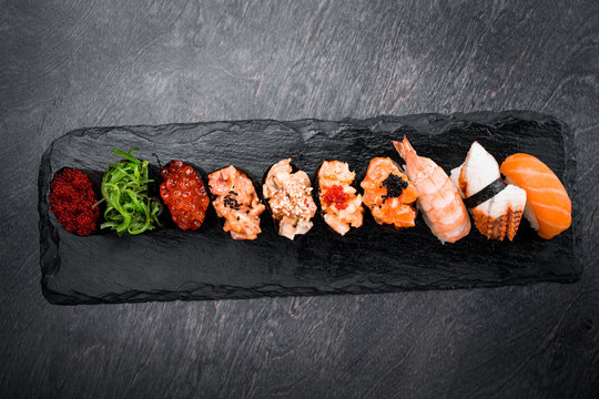 Tasty and delicious traditional japanese sushi roll with seafood and fish on black wooden background
