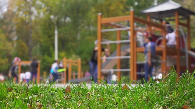 Children and parents having fun on playground in park. Selective focus on foreground, slow motion.