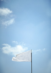 White Flag blowing in the wind with a blue sky