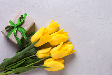 Bright yellow tulips and box with gift  on grey textured backgro