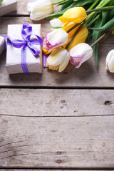Yellow and white spring tulips and wrapped  box with present  on