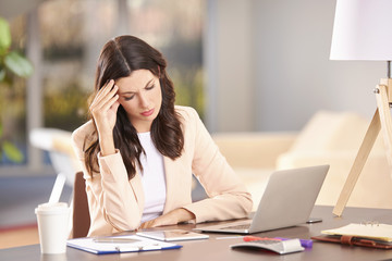 Hard day in the office. Shot of a young businesswoman looking stressed while sitting in her office in front of laptop.
