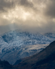 Dark and moody storm clouds over snowcapped Cumbrian mountains.