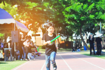 School boy is running during relay race of sport day festival