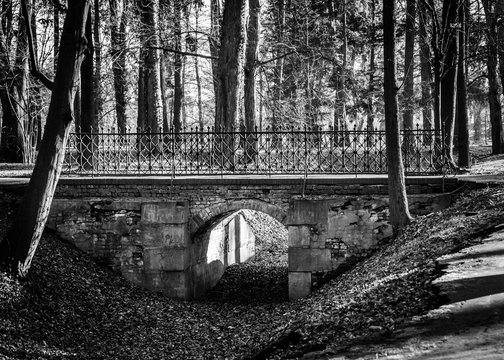 Fototapeta Stary kamienia most z metalu poręczem w parku. Czarno-białe zdjęcie.