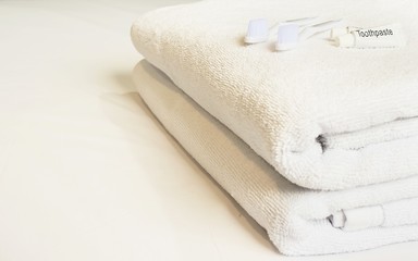 Hotel towel set with toothbrush and toothpaste on white bed