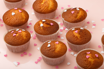 Muffins in paper forms and a lot of small sugar hearts on a mirrored background. Valentine's Day breakfast