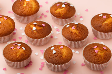 Muffins in paper forms and a lot of small sugar hearts on a mirrored background. Valentine's Day breakfast