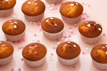 Muffins in paper forms and a lot of small sugar hearts on a mirrored background. Valentine's Day breakfast