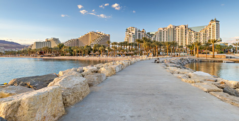 Evening at a public beach in Eilat - famous resort and recreational city in Israel. View from stone walking pier
