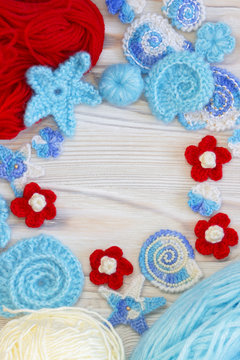 Marine background with cotton lace crochet craft elements: stars, shells, flowers and frame made of soft acrylic like wool yarn. Crocheted creative doilies. Decorative needlework, marine design