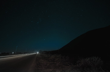 Beautiful night landscape of stars at sky and mountain silhouette near road with car trails. Road in the mountains under a starry gyres. Azerbaijan, Big Caucasus, Sheki
