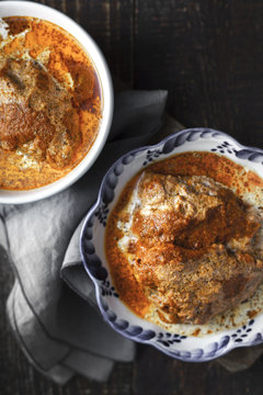 Juicy Butter chicken in two ceramic bowls on a dark background