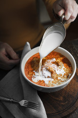 Woman pouring cream Butter chicken in a bowl