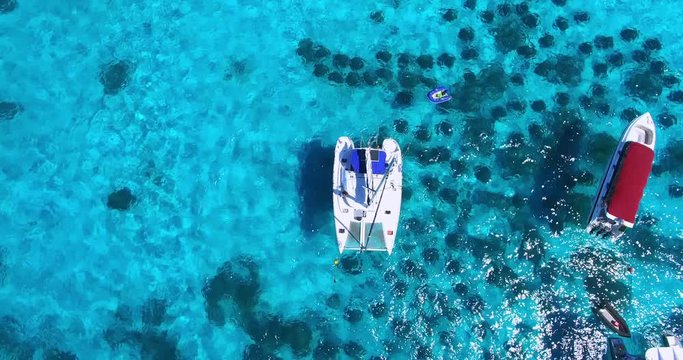 Racha Island Beach. Thailand, Phuket. Yachts , Catamarans and Boats sailing in crrystal clear blue water of ocean. Take off from ocean to sky. Catamaran in center of view. Aerial view. 4K.