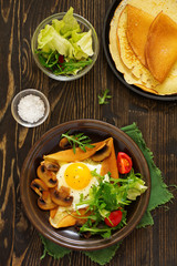 Pancakes with fried egg and fried mushrooms.