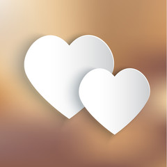 Two paper hearts on bronze background